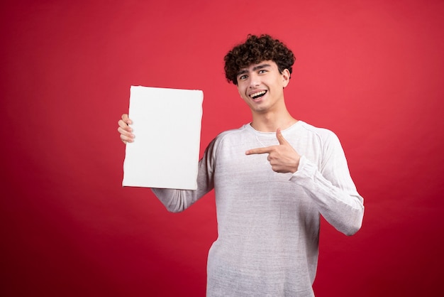 Young man pointing at empty canvas  .