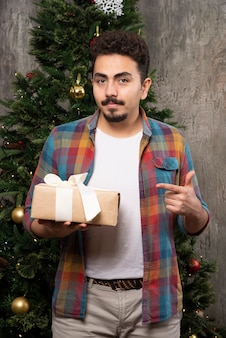 Молодой человек указывая пальцем на свой подарок.