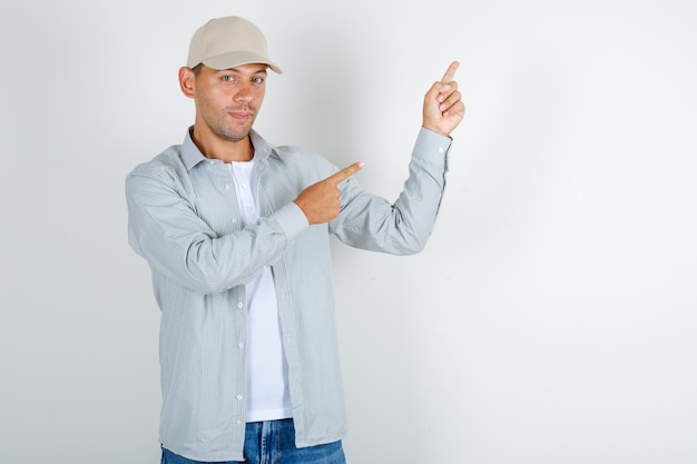 Young man pointing fingers at something in t-shirt with cap