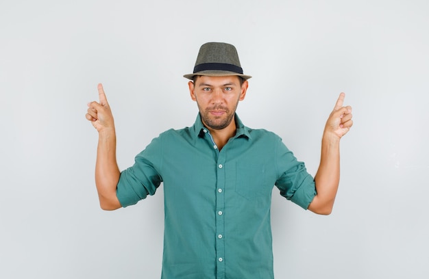 Free photo young man pointing fingers up in shirt