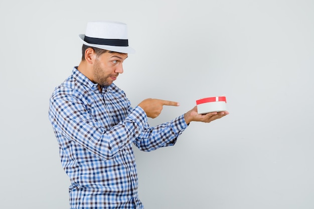 Young man pointing at gift box in checked shirt