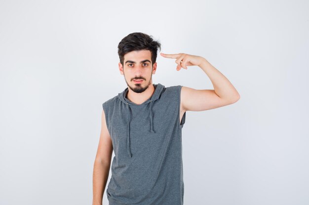 Young man pointing at himself in gray t-shirt and looking serious