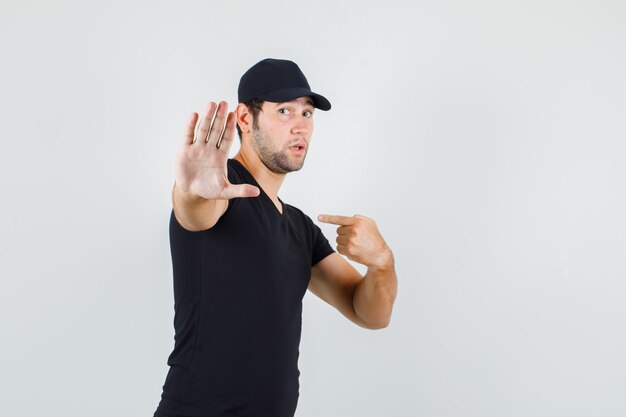 Young man pointing at himself with no gesture in black t-shirt