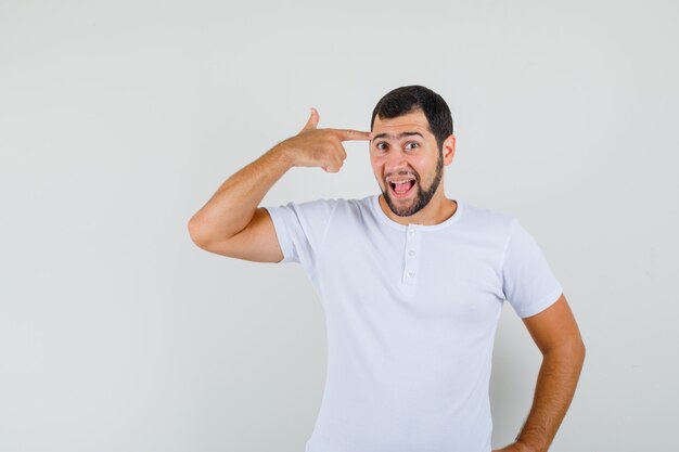 Young man pointing at his brain in t-shirt and looking omniscient. front view.