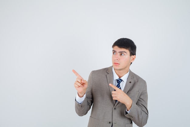 Young man pointing left with index fingers in formal suit