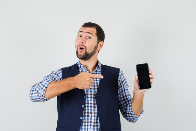 Young man pointing at mobile phone in shirt