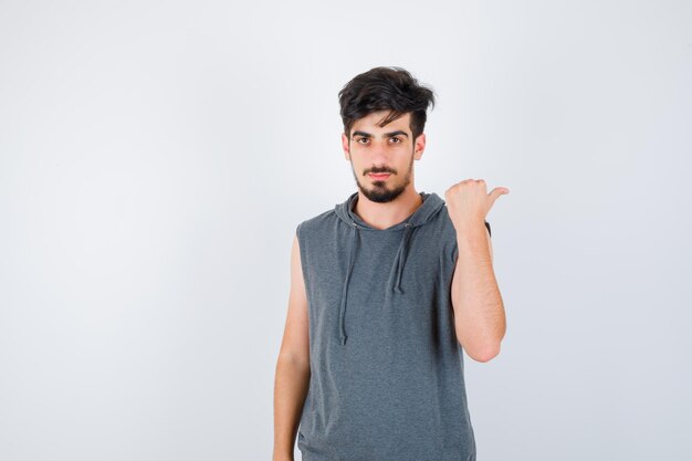 Young man pointing right in gray t-shirt and looking serious