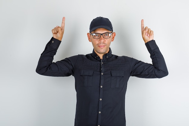 Free photo young man pointing up fingers in black shirt with cap