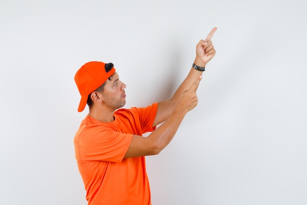오렌지 티셔츠와 모자를 가리키는 젊은 남자가 집중 찾고