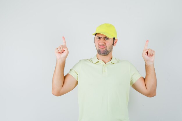 Young man pointing up in yellow uniform and looking hesitant.