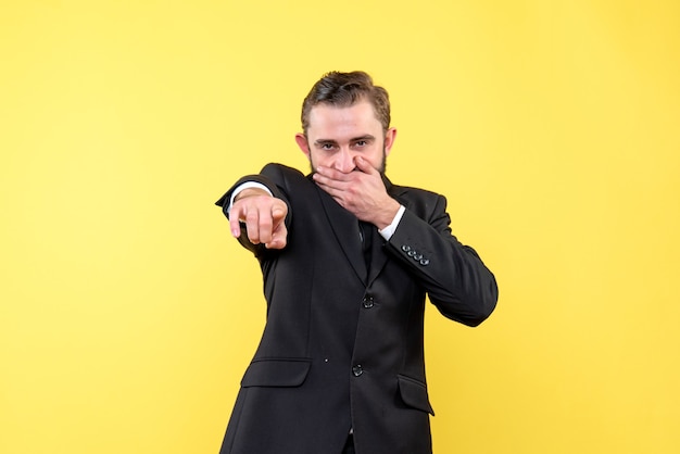 Free photo young man poiting something while holding hand on his mouth