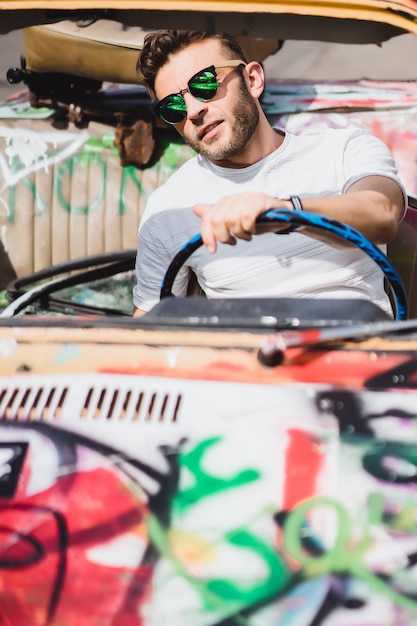 young man posing against the backdrop of a vintage car