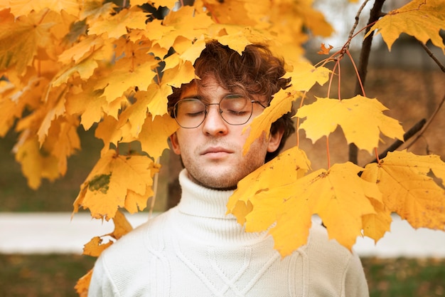 Young man posing in autumn leaves