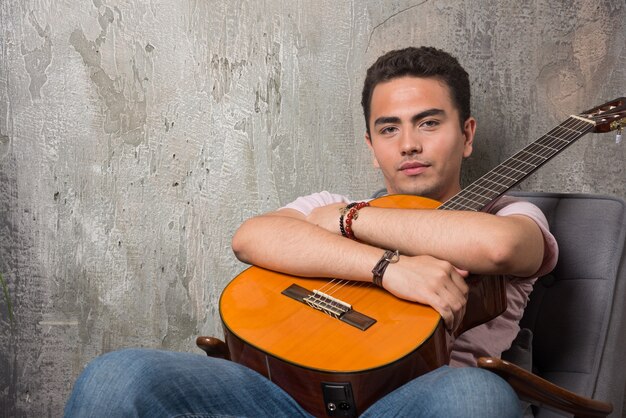 Young man posing at camera while gripping guitar.