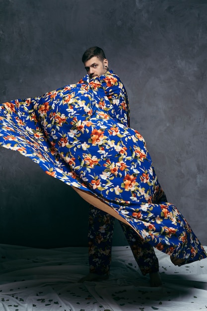 Free photo young man posing in floral drape against grey wall