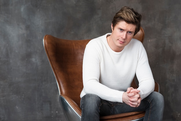 Free photo young man posing on leather armchair