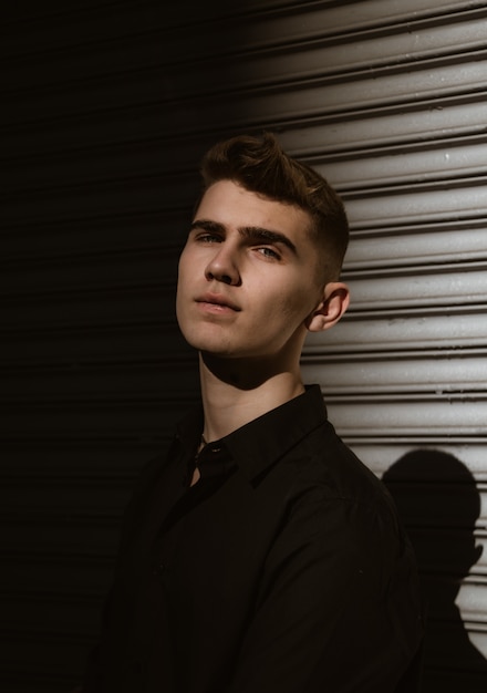 Young man posing on metallic fence