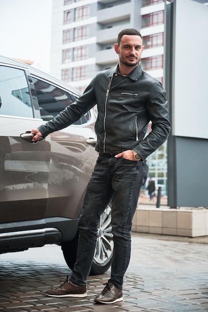 Free photo young man posing near his modern car