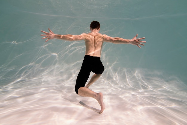 Foto gratuita giovane uomo in posa sommerso sott'acqua