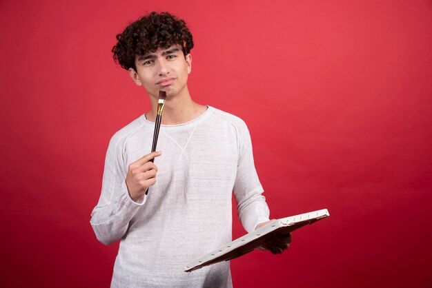 Young man posing with brush and empty canvas.