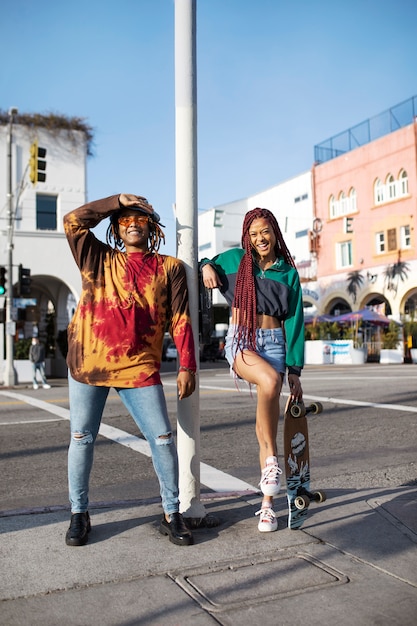 Foto gratuita giovane in posa con il suo amico con uno skateboard in città