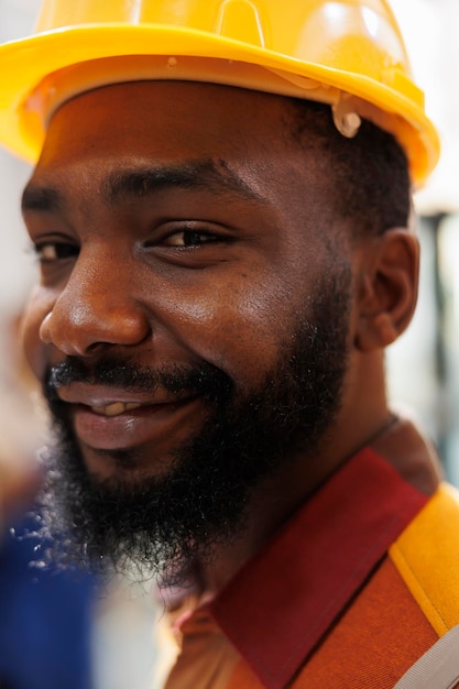 Free photo young man post office loader smiling and looking at camera portrait. warehouse manager wearing protective helmet managing parcels dispatching in stockroom face close up portrait