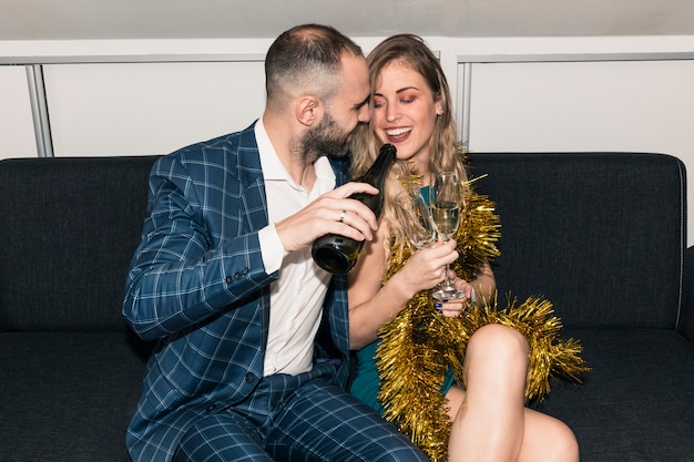 Foto gratuita giovane che versa champagne in un bicchiere di donna