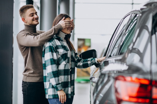 Young man presents a mcar to his girlfriend in a car showroom