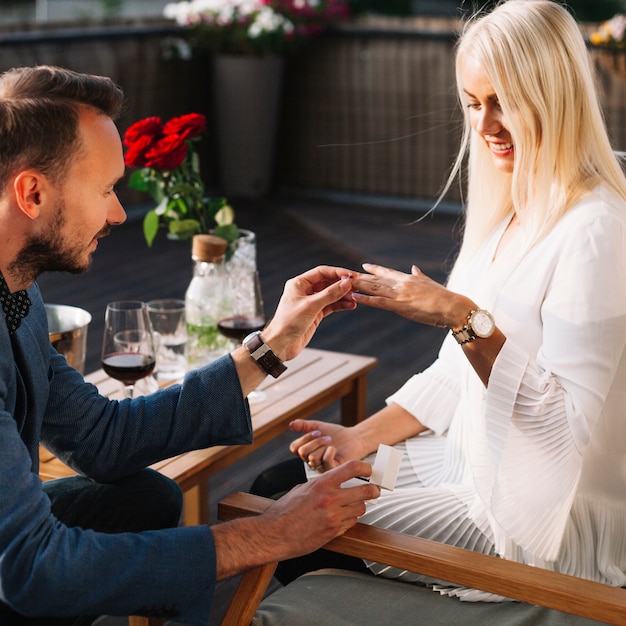 Young man proposing to smiling beautiful woman outdoors