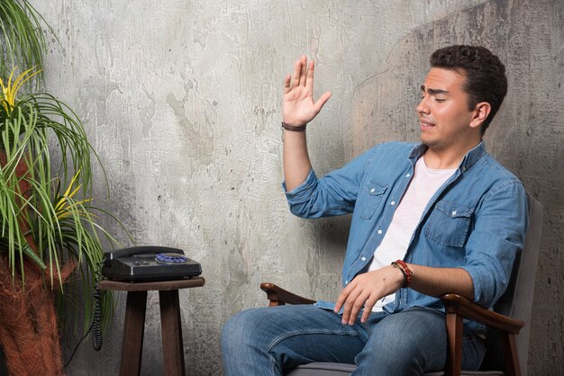 Young man put down the telephone and sitting on chair. High quality photo