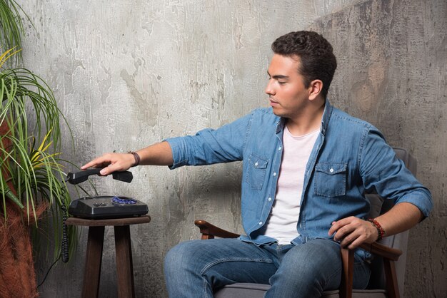 Young man put down the telephone and sitting on chair. High quality photo