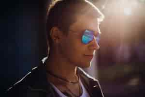 Free photo young man puts on sunglasses standing outside