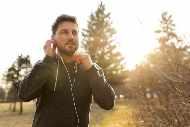 Young man putting on earphones outdoors