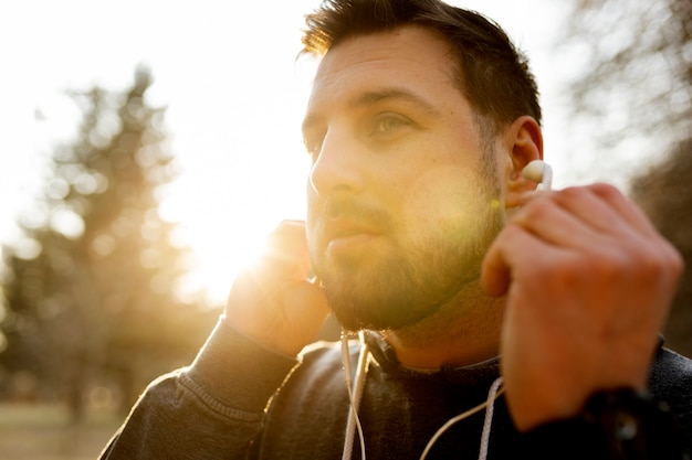 Young man putting on earphones outdoors