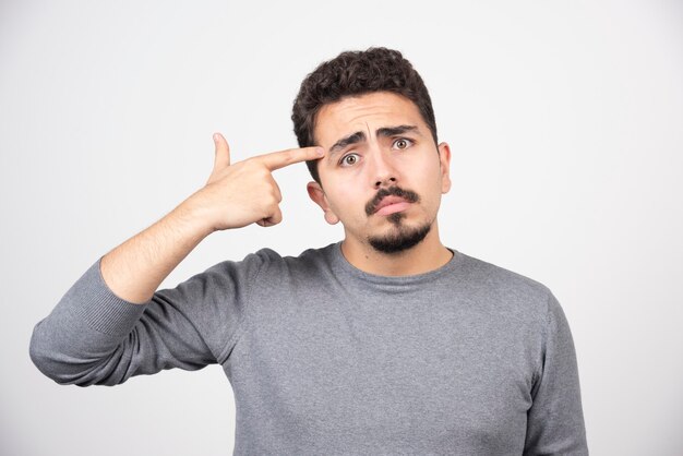 A young man putting his finger in head.