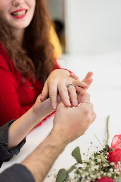 Молодой человек ставит обручальное кольцо на палец женщины