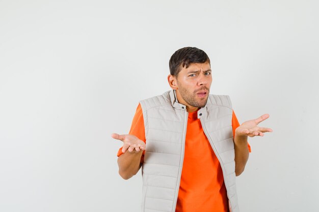 Young man raising hands in puzzled gesture in t-shirt, jacket