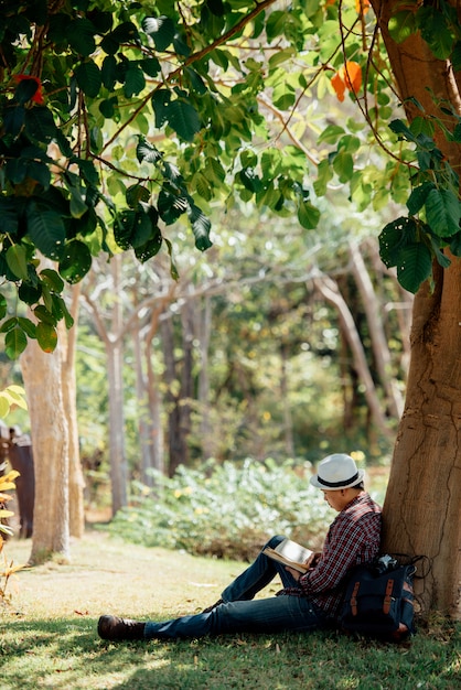 Бесплатное фото Книга чтения молодого человека на лужайке летом