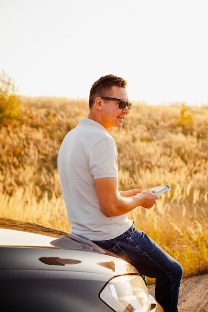 Foto gratuita giovane che legge un libro sul cofano dell'auto