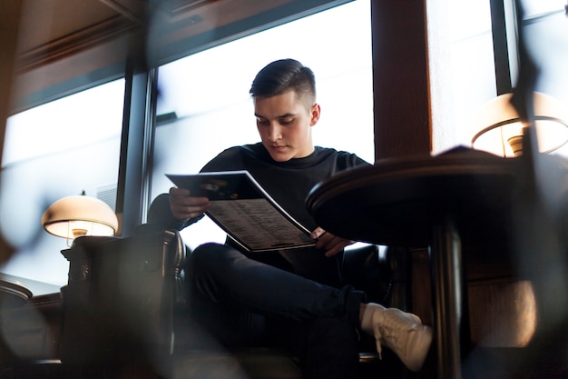 Молодой человек, читающий меню в кафе