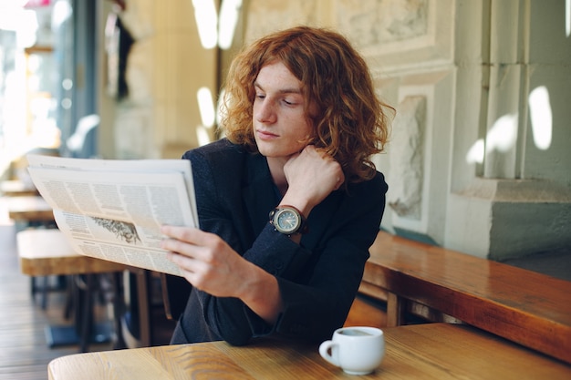 Young man reading a newspaper in the morning