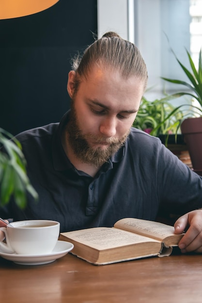 若い男がカフェでお茶を飲みながら本を読む