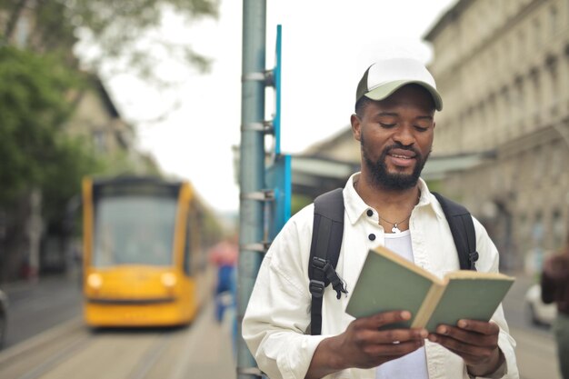 若い男が路面電車の駅で本を読む