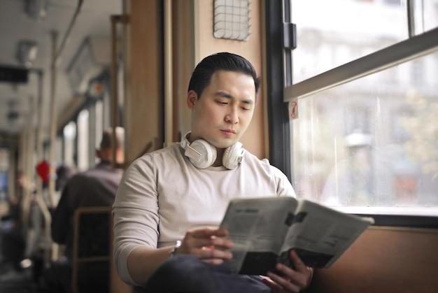 young man reads a newspaper on a tram