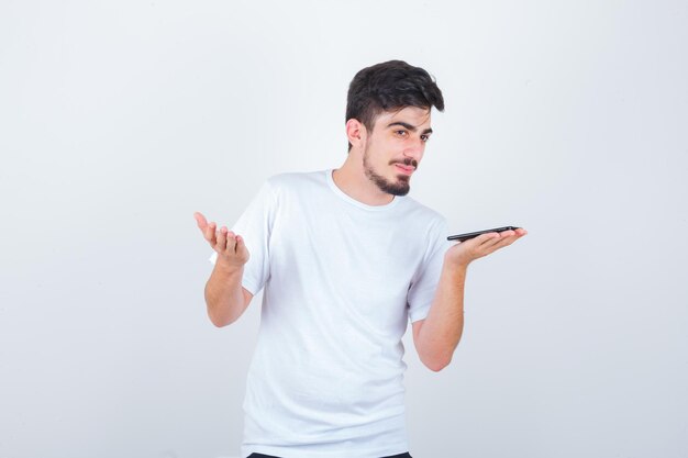 Young man recording voice message on mobile phone in t-shirt and looking confident