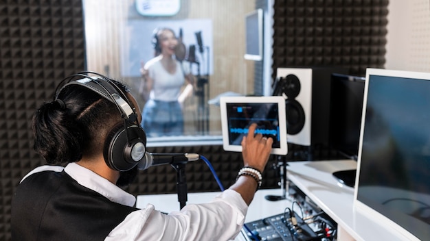 Giovane che registra una donna che canta in una stazione radio