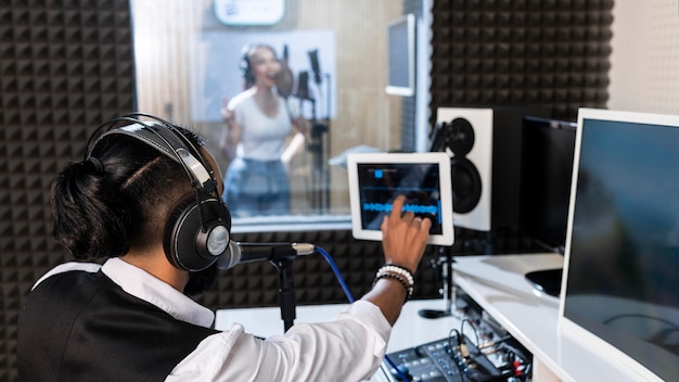 라디오 방송국에서 노래하는 여자를 녹음하는 젊은 남자