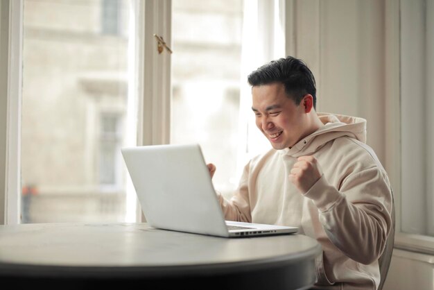 젊은 남자는 컴퓨터 앞에서 기뻐한다