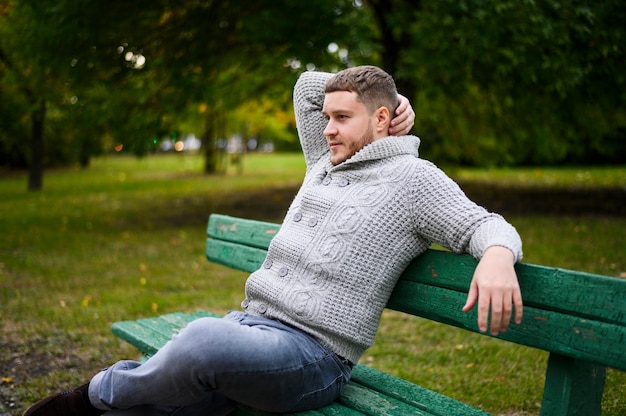 Free photo young man relaxing on bench in park