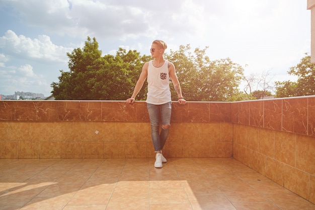 Young man relaxing, enjoying a sunny day while standing on a bui